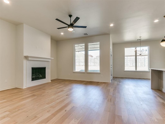 unfurnished living room featuring light hardwood / wood-style floors and ceiling fan with notable chandelier