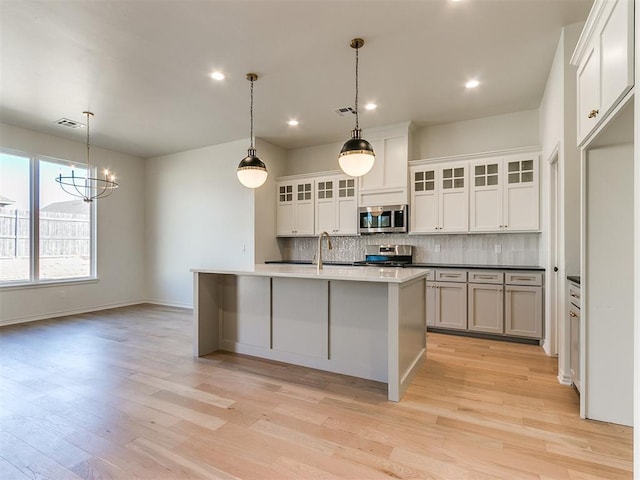 kitchen featuring light hardwood / wood-style floors, white cabinetry, stainless steel appliances, and an island with sink