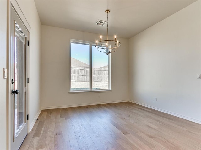 spare room with light wood-type flooring and a notable chandelier