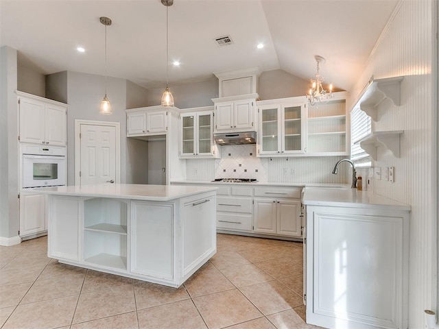 kitchen featuring white cabinets, oven, sink, gas stovetop, and a kitchen island