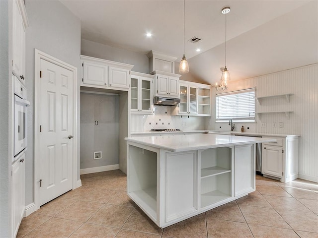 kitchen featuring white oven, white cabinetry, a center island, and vaulted ceiling