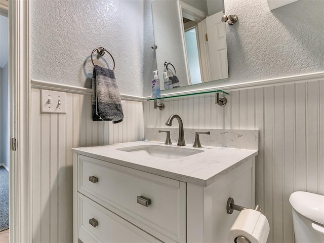 bathroom with wood walls, vanity, and toilet