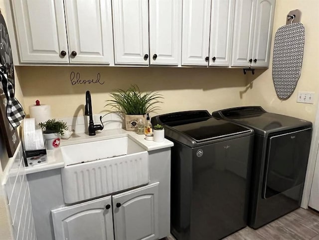 laundry area featuring cabinets, light wood-type flooring, separate washer and dryer, and sink