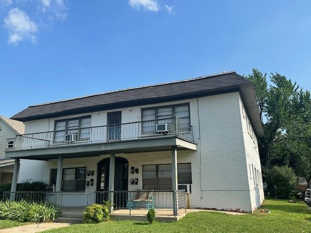 view of front facade with cooling unit, a porch, a balcony, and a front lawn