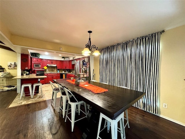 dining area with dark hardwood / wood-style flooring and an inviting chandelier