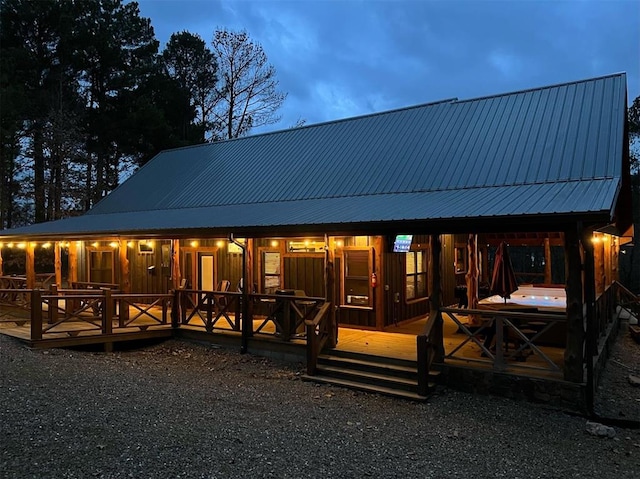 back house at dusk featuring a hot tub and a deck