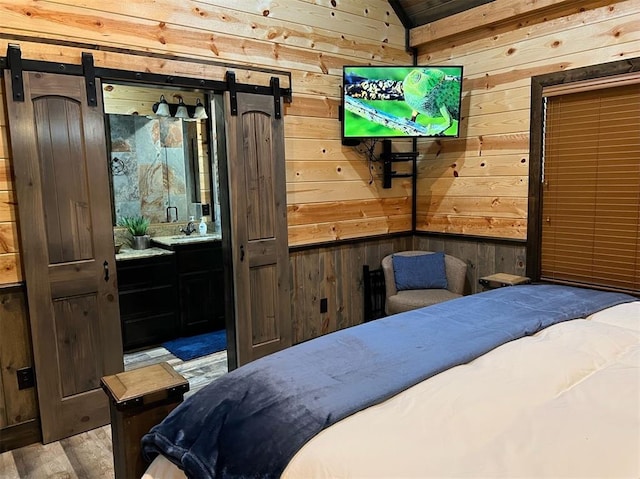 bedroom featuring a barn door, light hardwood / wood-style floors, lofted ceiling, and wood walls