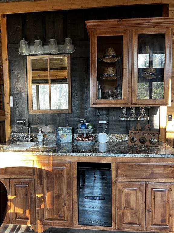 bar featuring dark stone countertops, sink, beverage cooler, and tasteful backsplash