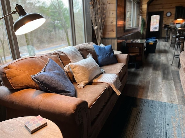 living room with a wealth of natural light, wooden walls, and hardwood / wood-style flooring