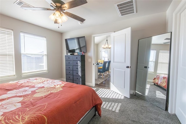 carpeted bedroom with ceiling fan with notable chandelier