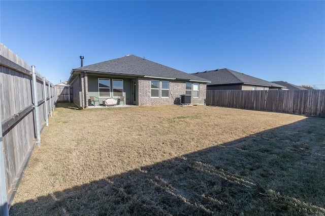 rear view of property featuring central AC and a yard