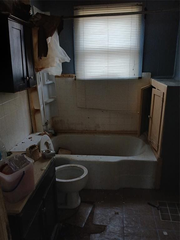 bathroom with a bathing tub, tile patterned flooring, toilet, and tile walls