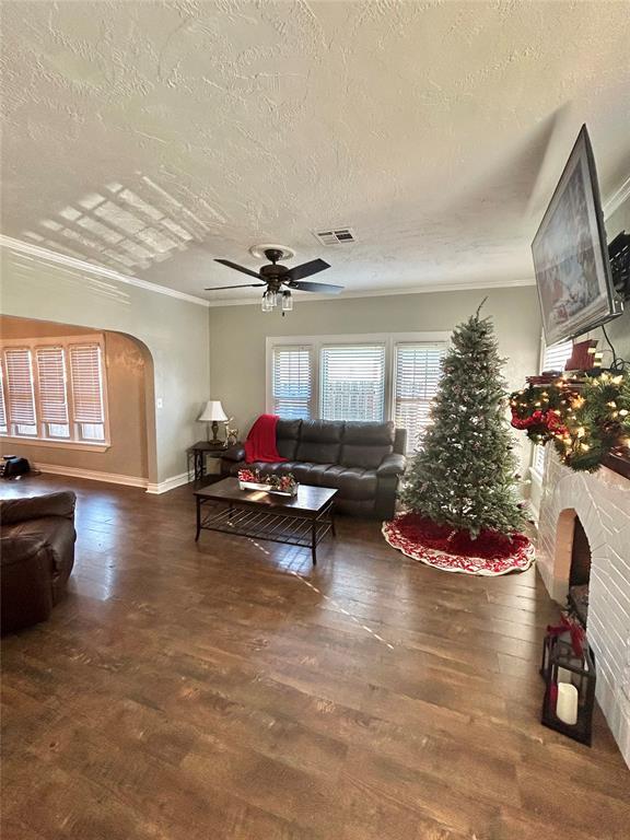 living room with a textured ceiling, crown molding, and dark wood-type flooring