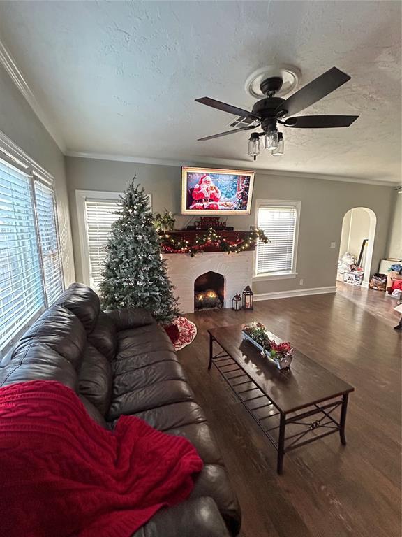 living room featuring crown molding, hardwood / wood-style floors, ceiling fan, and a textured ceiling