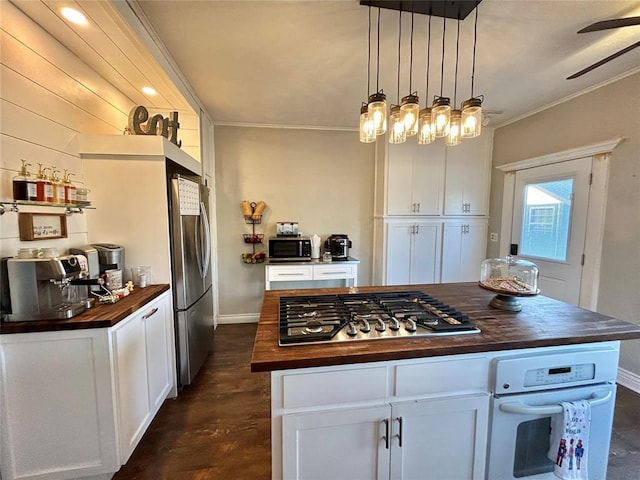 kitchen featuring white cabinets, a center island, stainless steel appliances, and butcher block counters