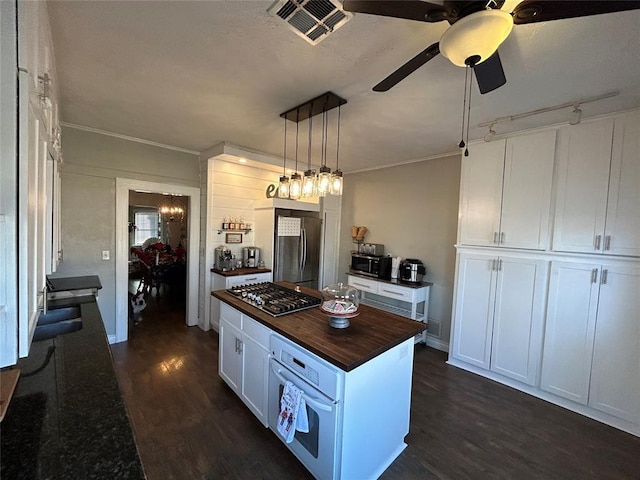 kitchen featuring appliances with stainless steel finishes, dark wood-type flooring, decorative light fixtures, white cabinetry, and a kitchen island