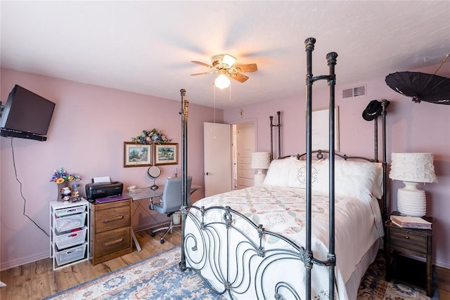 bedroom with ceiling fan, wood finished floors, visible vents, and baseboards