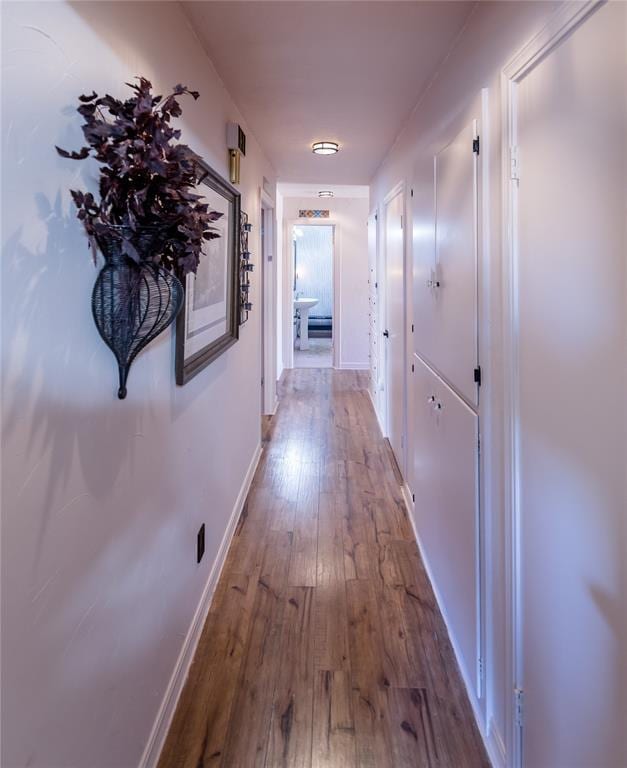 corridor with hardwood / wood-style floors and baseboards