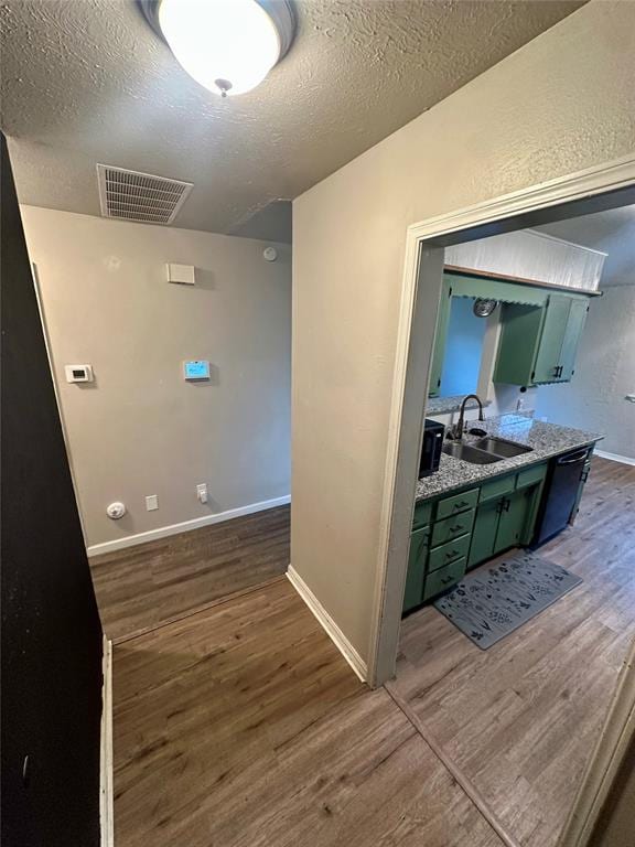 corridor with a textured ceiling, dark hardwood / wood-style floors, and sink