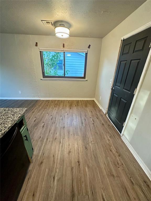 unfurnished dining area featuring a textured ceiling and hardwood / wood-style flooring