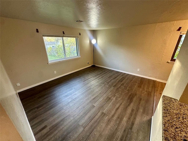 spare room with a textured ceiling and dark wood-type flooring