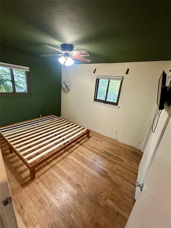 bedroom featuring ceiling fan, light wood-type flooring, and a textured ceiling