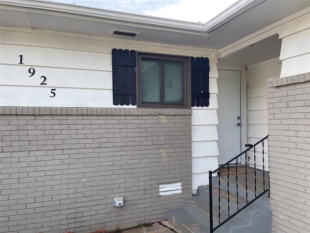 doorway to property with brick siding and visible vents