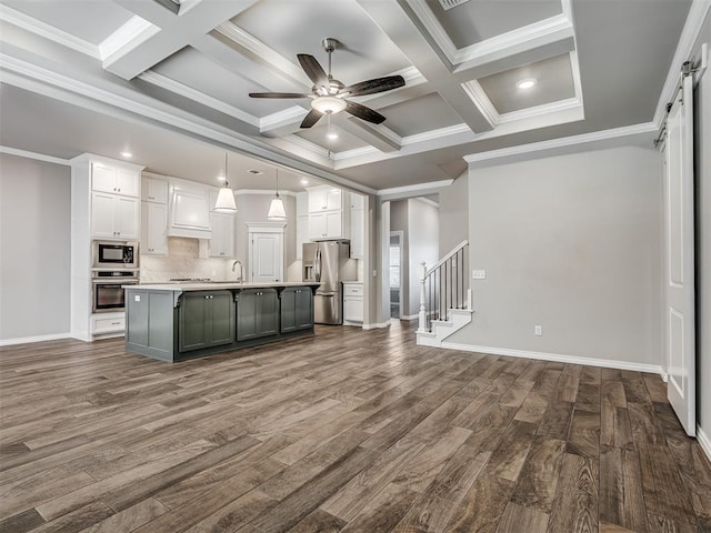 kitchen featuring pendant lighting, stainless steel appliances, white cabinetry, and a kitchen island with sink