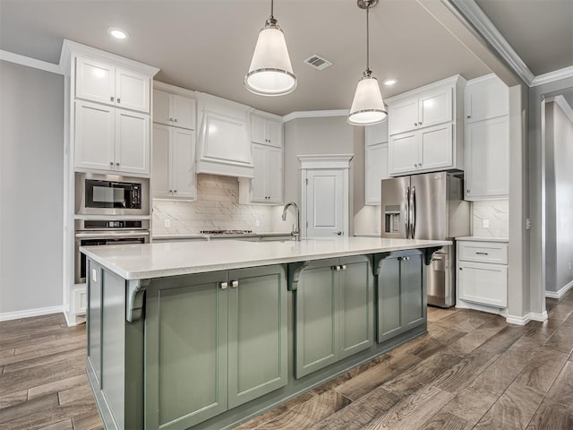 kitchen with white cabinetry, a center island with sink, decorative light fixtures, and appliances with stainless steel finishes