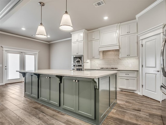 kitchen with dark wood-type flooring, white cabinetry, a center island with sink, and pendant lighting