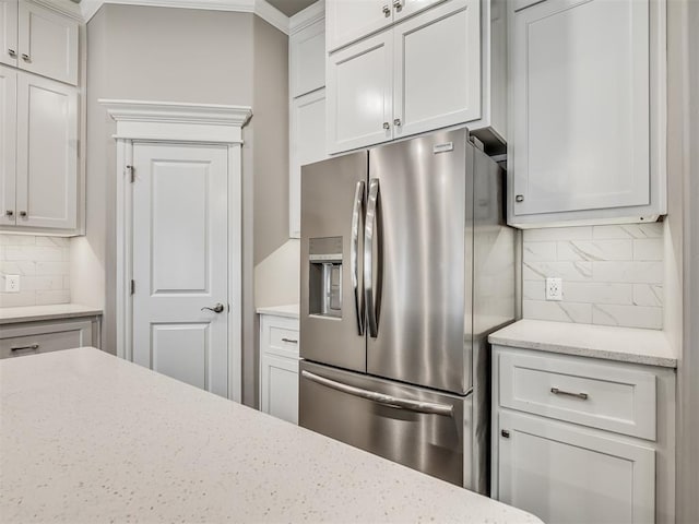 kitchen with white cabinets, stainless steel fridge, and tasteful backsplash