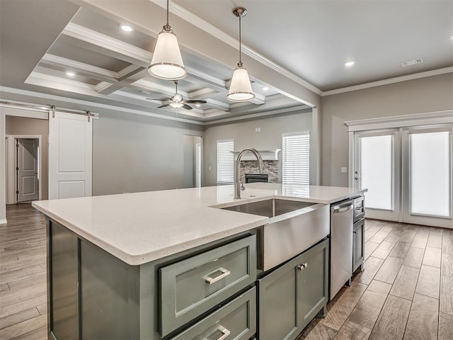 kitchen featuring sink, coffered ceiling, a barn door, stainless steel dishwasher, and a kitchen island with sink