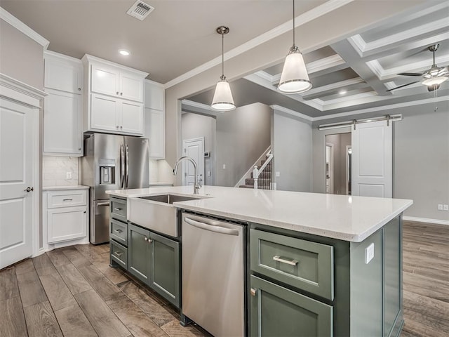 kitchen featuring stainless steel appliances, a barn door, green cabinets, a center island with sink, and white cabinets