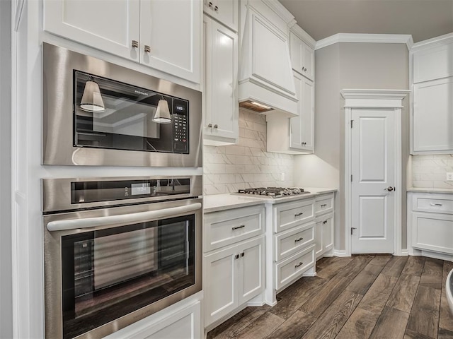 kitchen with custom exhaust hood, stainless steel appliances, crown molding, white cabinets, and dark hardwood / wood-style floors