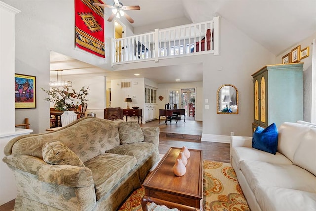 living room featuring ceiling fan with notable chandelier, hardwood / wood-style flooring, and high vaulted ceiling