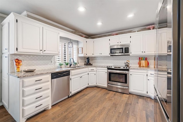 kitchen featuring stainless steel appliances, crown molding, sink, light hardwood / wood-style floors, and white cabinetry