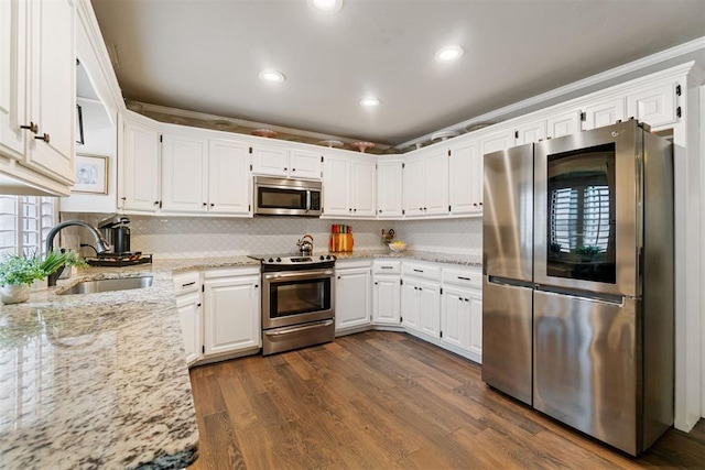 kitchen featuring white cabinets, sink, dark hardwood / wood-style flooring, light stone counters, and stainless steel appliances