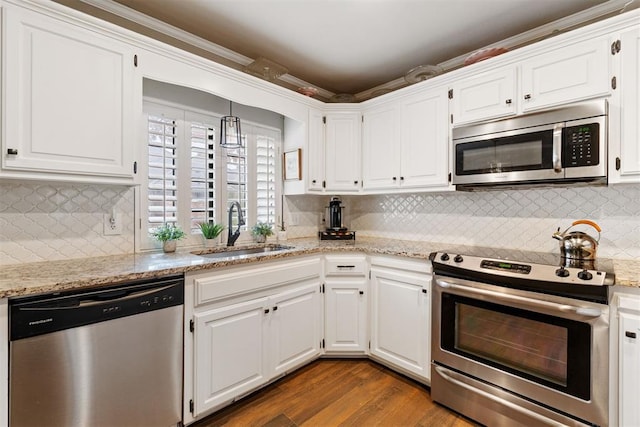 kitchen with light stone counters, stainless steel appliances, sink, wood-type flooring, and white cabinetry