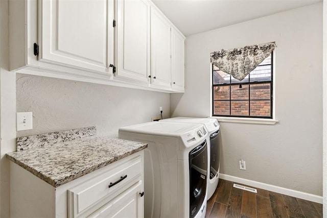 laundry room featuring cabinets, dark hardwood / wood-style floors, and washing machine and clothes dryer