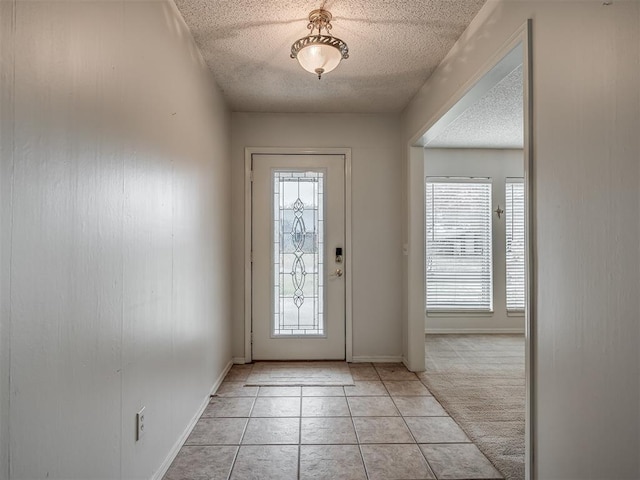 foyer featuring light colored carpet and a textured ceiling