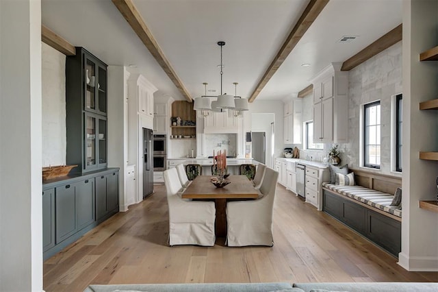 dining space featuring beamed ceiling and light wood-type flooring