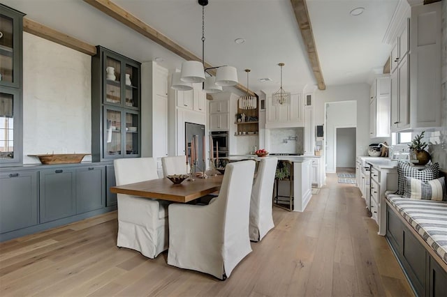 dining area with light hardwood / wood-style floors and beamed ceiling