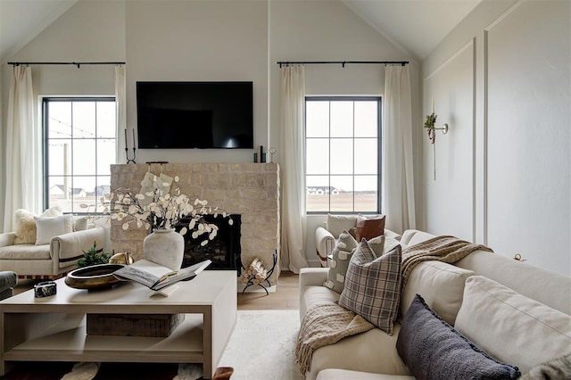 living room with lofted ceiling, a tile fireplace, and light hardwood / wood-style floors