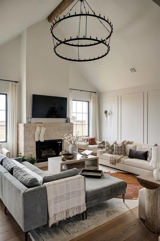 living room featuring beam ceiling, wood-type flooring, a wealth of natural light, and high vaulted ceiling