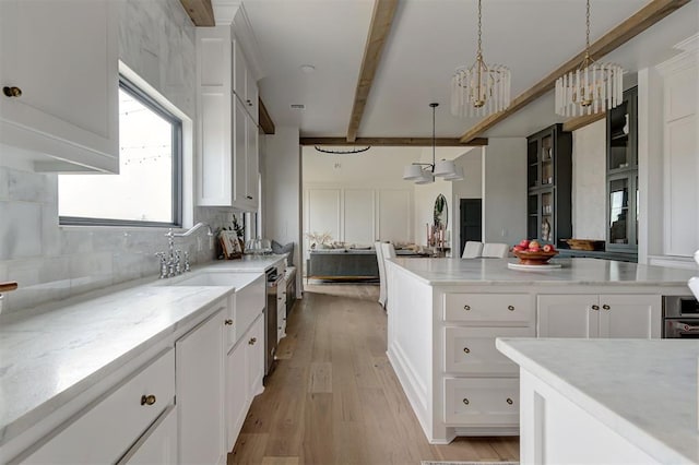 kitchen featuring decorative backsplash, white cabinets, hanging light fixtures, light hardwood / wood-style flooring, and beamed ceiling