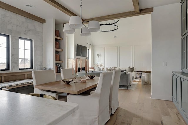 dining room featuring a notable chandelier, beamed ceiling, and light hardwood / wood-style floors