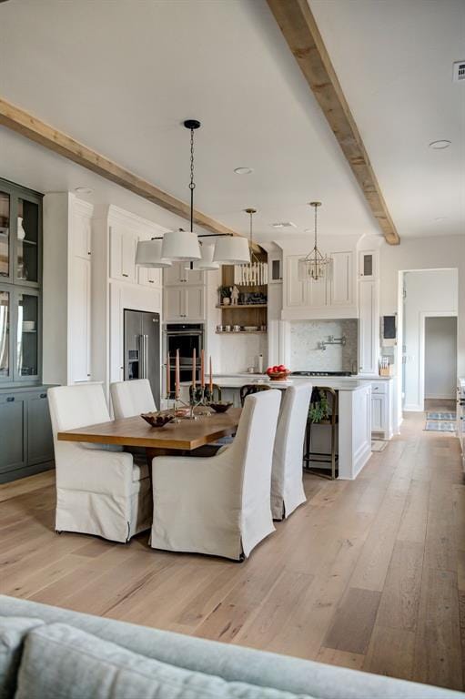 interior space with beam ceiling and light hardwood / wood-style flooring