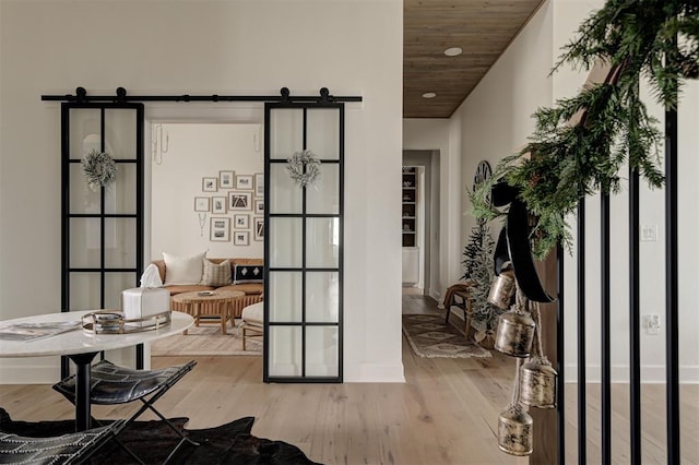 entryway featuring light hardwood / wood-style floors, wooden ceiling, and a barn door