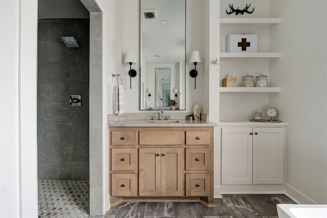 bathroom featuring a tile shower and vanity