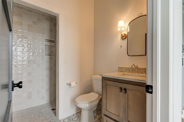 bathroom with toilet, vanity, tile patterned flooring, and a tile shower